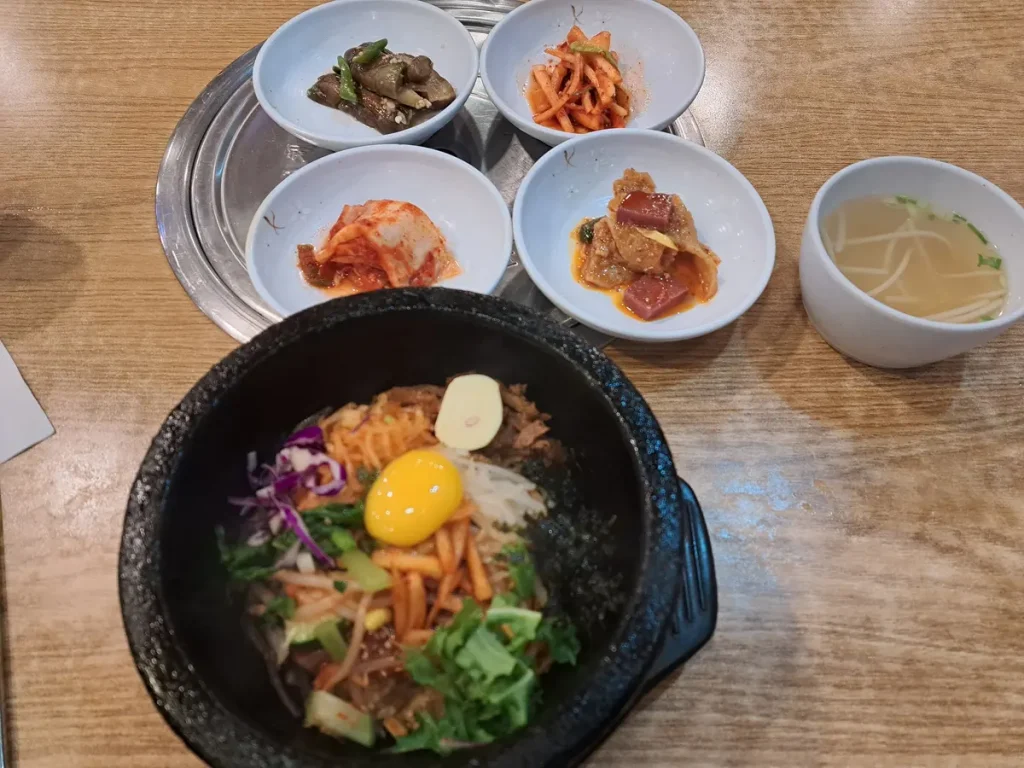 ein leckerer Bibimbap mit verschiedenen Kimchi und einer Suppe als Beilage