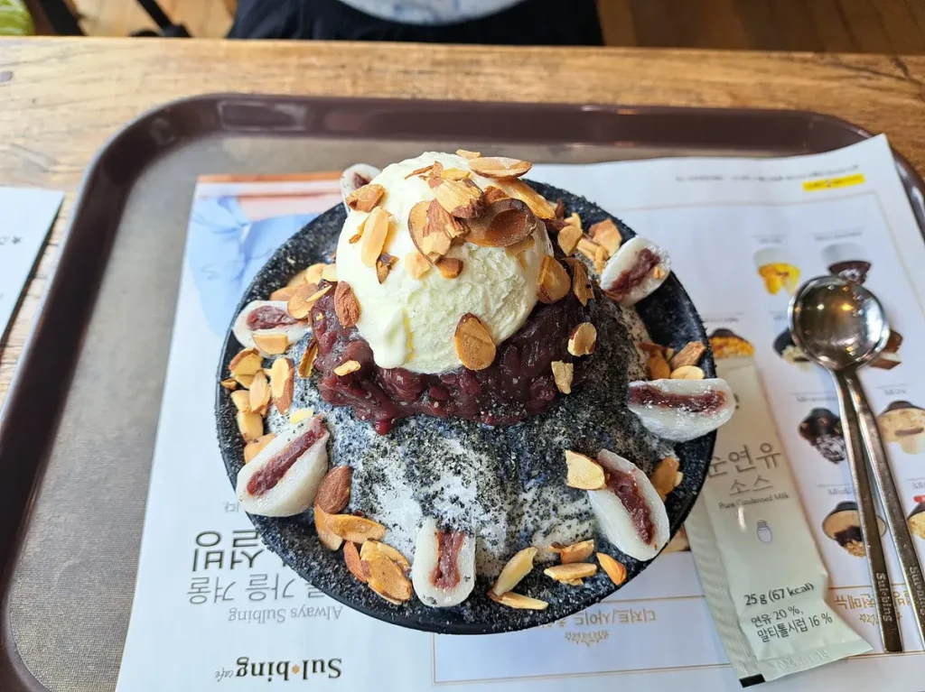 Zum Dessert gibt es Bingsu - die Basis besteht aus sehr fein geraspeltem Eis, das mit Kondensmilch übergossen wird. Unser Topping besteht aus schwarzem Sesam, Mandelscheiben, roten Adzukibohnen, Mochi und Vanilleglacé.