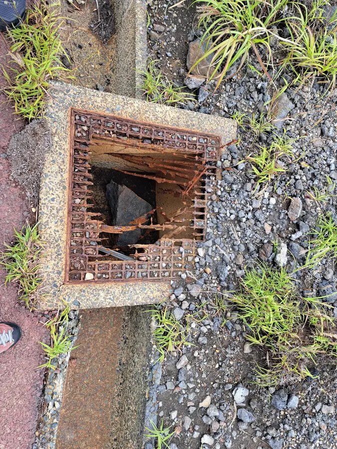 Hier sieht man die Auswirkungen des Vulkans, das Metallgitter ist verrostet und korrodiert und durch einen Steinbrocken zerstört.