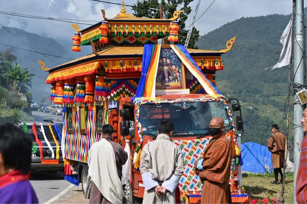 farbig geschmückter Lastwagen, in dem eine Statue des blaubärtigen Zhabdrung Ngawang Namgyal («the man who unified our country») von Thimphu nach Punakha transportiert wird