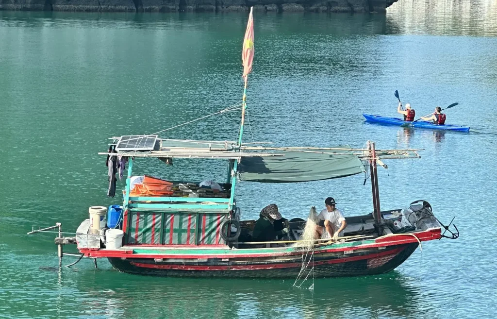 Fischerboot unterwegs und dahinter die Kajakfahrer.