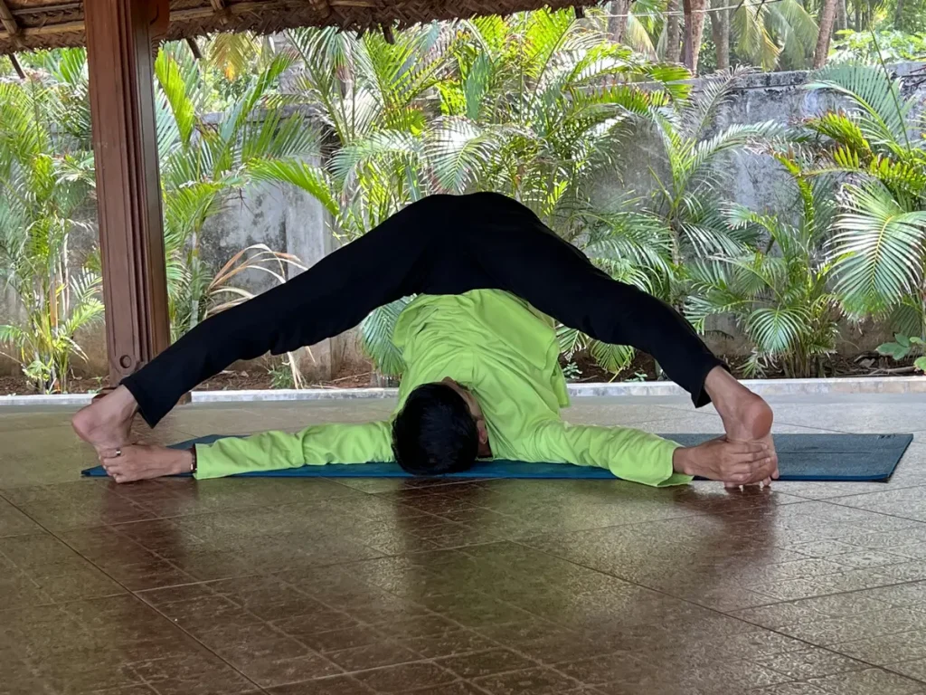 Der Yogalehrer Naveen präsentiert die «Offene Winkelhaltung» Variante von Upavistha Konasana