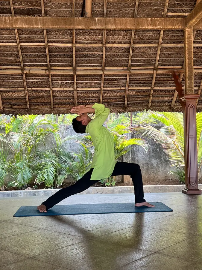 Der Yogalehrer Naveen präsentiert die «Krieger Position 1 / Virabadrasana 1»